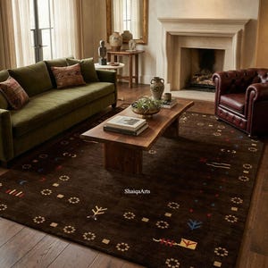 May include: A living room scene featuring a dark brown rug with a geometric pattern. The rug is the focal point, complemented by a green sofa, a wooden coffee table, and a leather armchair. The room has a fireplace and a large mirror.