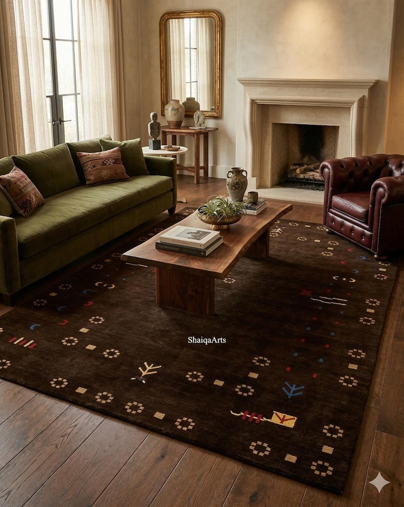 May include: A living room scene featuring a dark brown rug with a geometric pattern. The rug is the focal point, complemented by a green sofa, a wooden coffee table, and a leather armchair. The room has a fireplace and a large mirror.