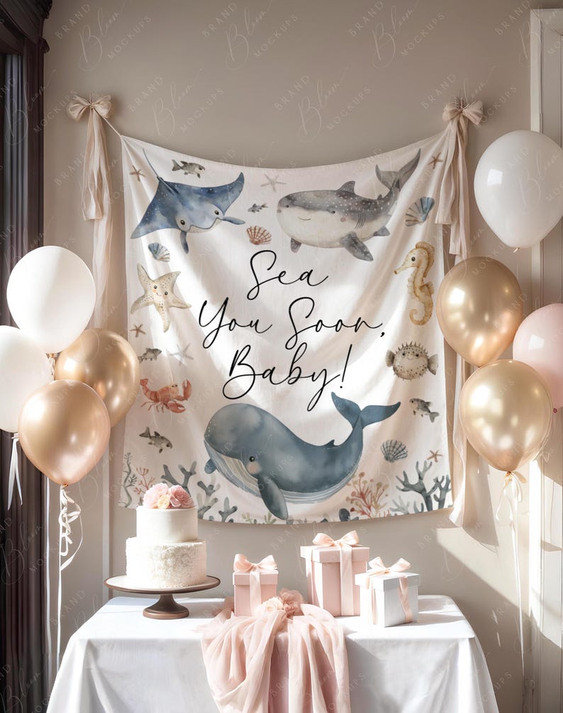 Pode incluir: Uma cena de ch&aacute; de beb&eacute; com uma faixa com criaturas marinhas e o texto "Sea You Soon, Baby!". Bal&otilde;es dourados, brancos e rosa decoram a sala. Um bolo de dois andares e presentes embrulhados est&atilde;o em uma mesa.