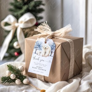 May include: A wrapped gift box with a tag featuring a polar bear and cub in a winter scene. The tag reads "thank you" and "JAMES BABY SHOWER Dec 24th, 202x". The box is wrapped in brown paper and tied with twine.