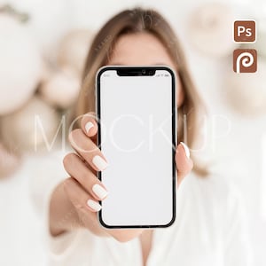 May include: A smartphone with a blank white screen is held up in front of a blurred background. The phone has a black border and a screen displaying the time 9:41. The person holding the phone has white nail polish.