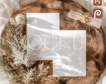 May include: A product mockup featuring two white paper cards with the word "MOCKUP" faintly visible. The cards are on a rustic wooden surface, surrounded by dried flowers, a woven ball, and a bouquet of roses.