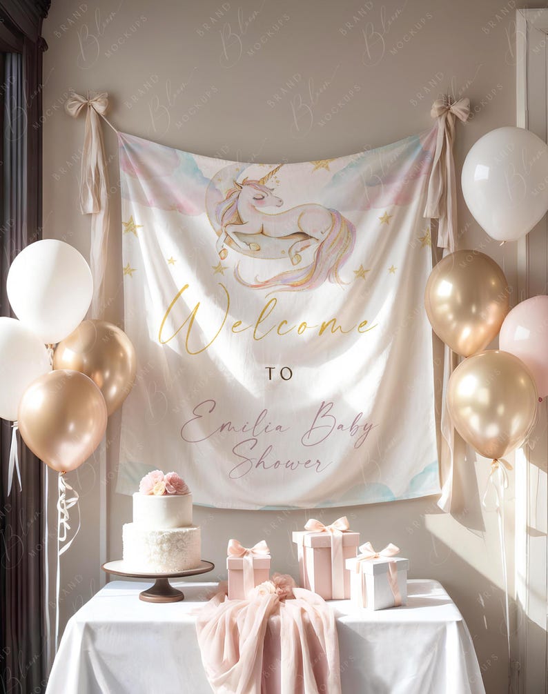 Pode incluir: Uma cena de ch&aacute; de beb&eacute; com uma faixa com uma ilustra&ccedil;&atilde;o de unic&oacute;rnio e as palavras "Welcome to Emilia Baby Shower". A mesa est&aacute; decorada com um bolo, presentes e bal&otilde;es dourados, brancos e rosa.