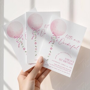 May include: Three white invitation cards with a pink balloon design and the text "little miss Onederful". The cards also include event details for a first birthday celebration, with a floral accent.
