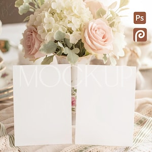 May include: A mockup image featuring two blank white cards in front of a floral arrangement. The flowers include light pink roses and white hydrangeas. The background has a soft, neutral color palette with lace and ribbon details.