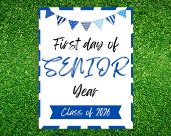May include: A white sign with blue accents and text that reads "First day of SENIOR Year Class of 2026." The sign has a blue and white striped border and a banner of blue pennants at the top. The sign is on a green grass background.