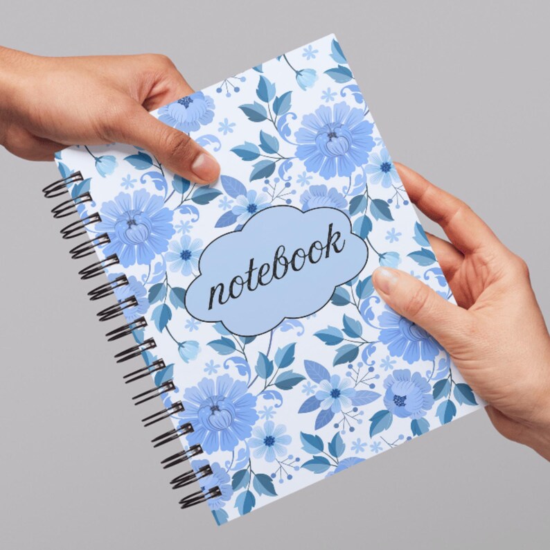 May include: A spiral-bound notebook with a floral design. The cover features blue flowers and leaves on a white background. The word "notebook" is written in a light blue cloud-shaped text box.