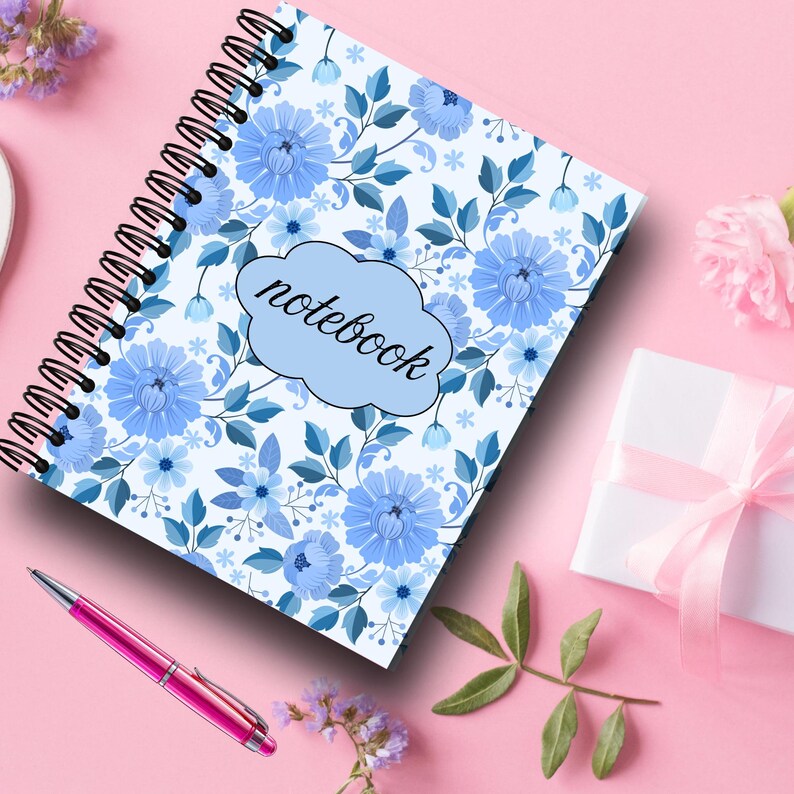 May include: A spiral-bound notebook with a floral design in shades of blue and white. The word "notebook" is written in a cloud-shaped design. A pink pen and a wrapped gift with a pink ribbon are also visible.
