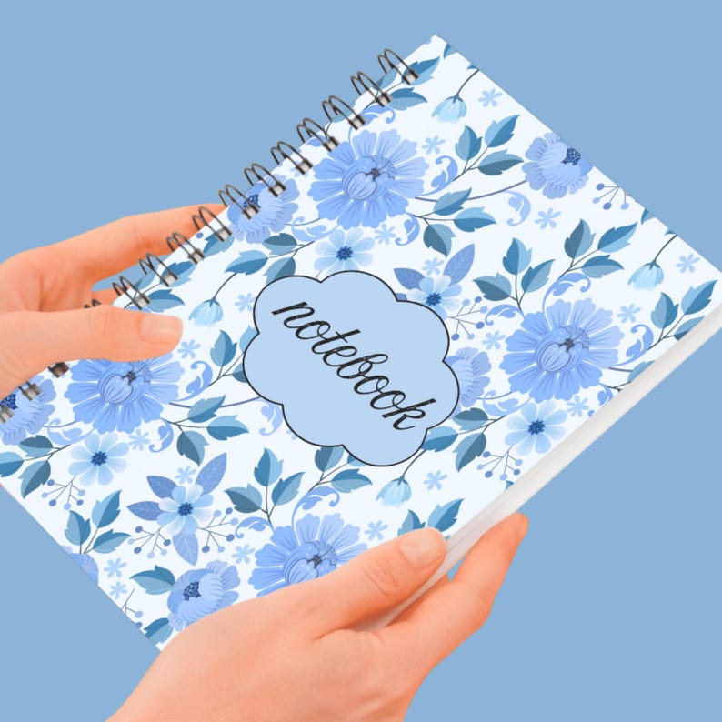 May include: Spiral-bound notebook with a floral design in shades of blue and white. The cover features a repeating pattern of stylized flowers and leaves, with the word "notebook" in a cloud-shaped text box.