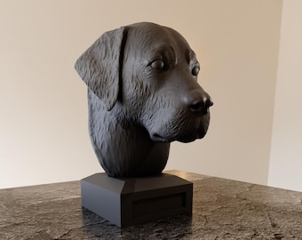 May include: A black dog head sculpture with detailed fur texture. The sculpture is mounted on a rectangular base. The dog's head is turned slightly to the side, showcasing its features. The sculpture is placed on a marble-like surface.