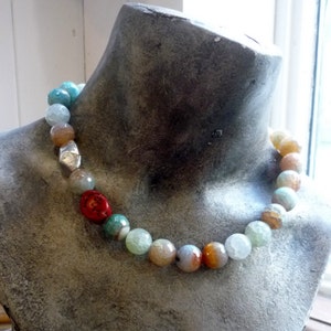 May include: A multi-colored agate bead necklace with a silver charm. The beads are various shades of blue, green, brown, and red.