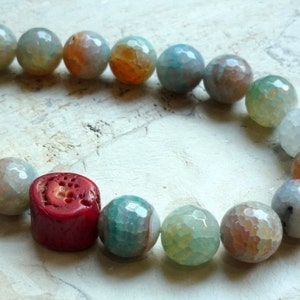 May include: A bracelet made of agate beads in shades of green, blue, and orange, with a single red coral bead.