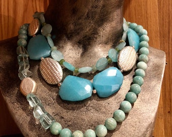 May include: A layered necklace with turquoise and silver beads. The necklace features large turquoise stones and silver accents.