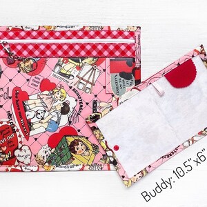May include: A pink zippered pouch with a quilted pattern and a white zipper. The pouch is decorated with a Valentine's Day theme print featuring hearts, flowers, and children. The pouch is open to reveal a white fabric lining. The text "Buddy: 10.5"x6" opened" is printed below the pouch.