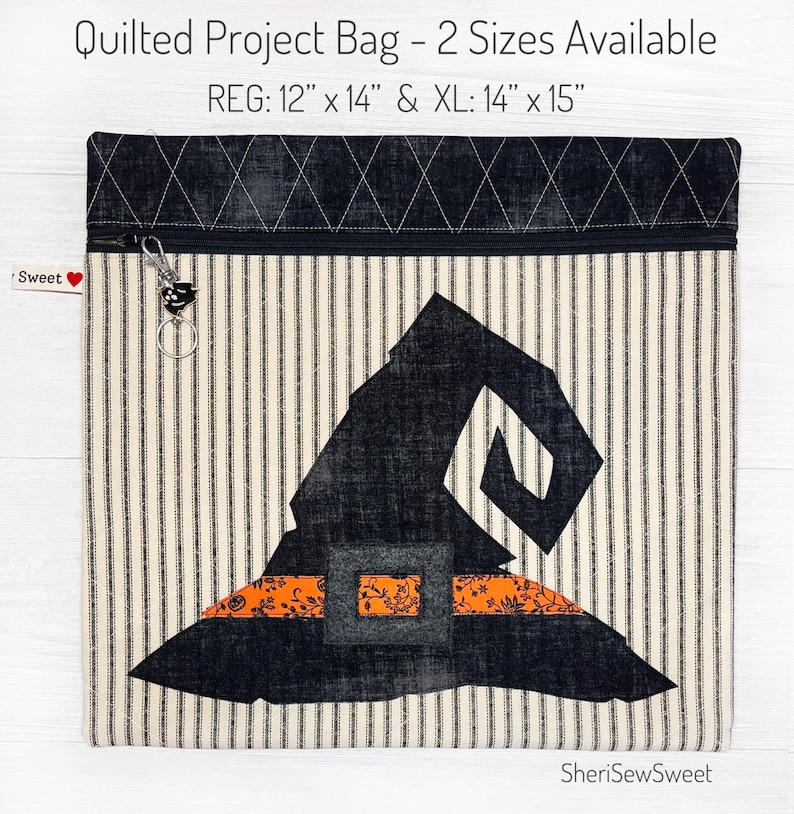May include: A quilted project bag with a witch hat design. The bag is made of a striped fabric with a black and white pattern. The bag has a zipper closure and a small charm attached to the zipper. The bag is available in two sizes: 12" x 14" and 14" x 15".