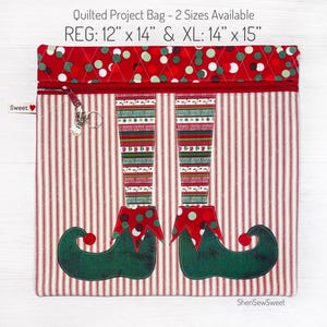 May include: Quilted project bag with a red and white striped fabric and an elf design. The bag has a zipper closure and comes in two sizes: 12" x 14" and 14" x 15".