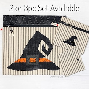 May include: A set of three witch hat-themed zippered pouches in black, white, and orange. The largest pouch features a large witch hat with a black brim and orange trim. The smaller pouches feature a smaller witch hat design. The pouches are made of a striped fabric with a white background and black stripes. The text "2 or 3pc Set Available" is printed at the top of the image.
