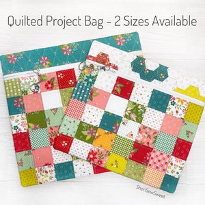 May include: Two quilted project bags with zipper closures. The larger bag is teal with white stitching and a floral pattern. The smaller bag is a patchwork of red, green, yellow, and pink squares with white stitching. Both bags have a zipper pull with a charm.
