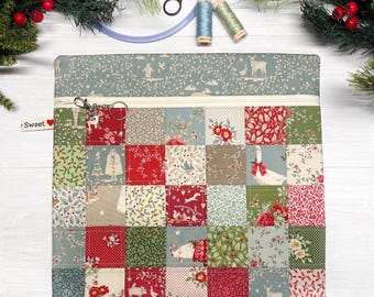 May include: A square fabric pouch featuring a patchwork design of various holiday-themed patterns in red, green, and cream. The pouch has a top zipper with a metal ring pull and a small white tag labeled Sweet with a red heart icon.