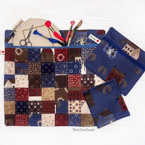 May include: Three zippered pouches with a patchwork design featuring houses, keys, and floral motifs. The pouches are made of blue and red fabric with a white background. The largest pouch has the words "Sweet" and "SheriSewSweet" printed on it.