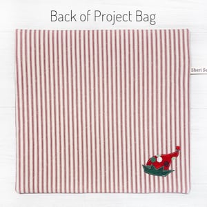 May include: Red and white striped fabric project bag with a green and red elf hat applique. The bag has a label that says "Sheri Se".