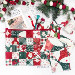 May include: Three red and green patchwork fabric zippered pouches with a white background and a variety of Christmas-themed prints. The pouches are arranged in a pyramid shape with the largest pouch at the bottom and the smallest pouch at the top. The pouches are decorated with red and white plaid fabric, a red star, and the words "Sweet" and "Fresh Cocoa".
