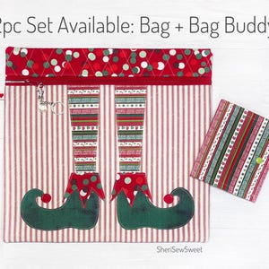 May include: A 2pc set of Christmas-themed elf leg-shaped zippered bags. The larger bag has a red and white striped fabric with a red polka dot fabric top. The smaller bag is a red and green striped fabric. The text "2pc Set Available: Bag + Bag Buddy" is at the top of the image.