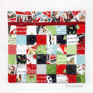 May include: A red and green zippered pouch with a patchwork design featuring images of Santa Claus, Christmas trees, and postage stamps. The pouch has a zipper closure and a silver zipper pull. The text "Merry Christmas" and "Santa, I hope us lots of" are visible on the pouch.