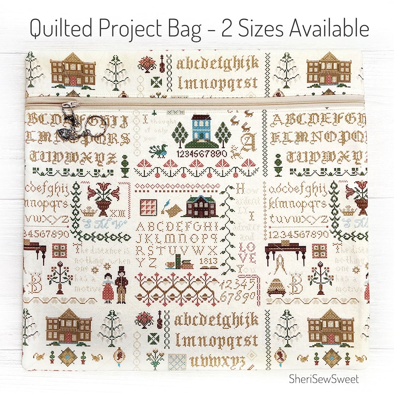 May include: Quilted project bag with a cream background, featuring cross-stitch style patterns of houses, trees, and alphabets. The bag has a beige zipper and the text "Quilted Project Bag - 2 Sizes Available".