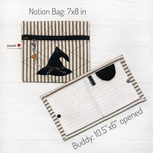 May include: A black and white striped fabric pouch with a zipper closure and a black witch hat applique. The pouch is labeled "Notion Bag: 7x8 in". The pouch is open and laid flat on a white wooden surface. The pouch is labeled "Buddy: 10.5 x 6" opened".