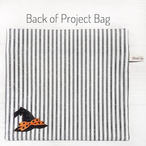 May include: The back of a white and black striped fabric project bag with a black witch hat with an orange polka dot bow. The bag has a label that says "Sheri Sews".