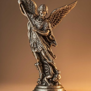 May include: A bronze-colored statue of an angel with large, detailed wings, holding a staff. The angel is depicted in a dynamic pose, standing on a base with a figure at its feet. The statue has intricate details and a classical aesthetic.