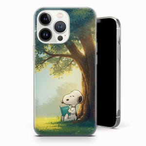 Puede incluir: Una funda transparente para teléfono con una ilustración de dibujos animados de Snoopy leyendo un libro bajo un árbol. El diseño representa una escena exterior serena con hierba verde y un gran tronco de árbol. La funda está diseñada para un smartphone.