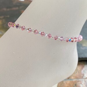 May include: A delicate anklet made with small pink and clear crystal beads.