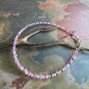 May include: A delicate anklet made with small pink and clear crystal beads. The anklet has a silver clasp.