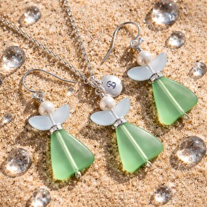 Puede incluir: Un conjunto de collar y pendientes de plata con colgantes en forma de &aacute;ngel. Los colgantes tienen cuerpos verde claro, cabezas de perlas y alas azul claro. Los pendientes tienen cierres de gancho. El collar tiene un peque&ntilde;o dije con el n&uacute;mero 8.