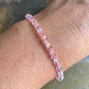 May include: A delicate bracelet made of pink and clear crystal beads. The bracelet is strung on a clear elastic cord and is approximately 7 inches in length.