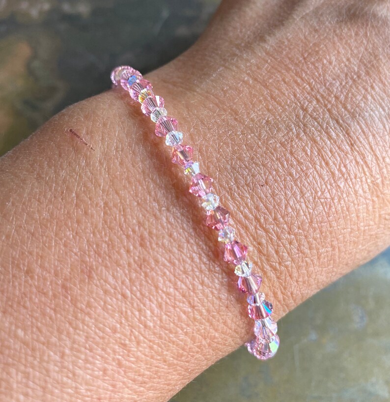 May include: A delicate bracelet made of pink and clear crystal beads. The bracelet is strung on a clear elastic cord and is approximately 7 inches in length.