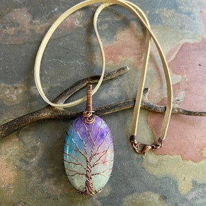 May include: A copper wire tree of life pendant with a colorful agate stone. The pendant is on a light brown leather cord.