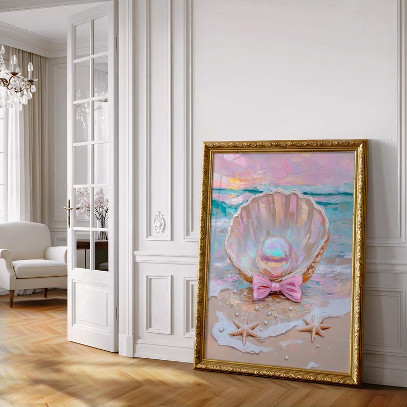 Puede incluir: Pintura enmarcada que representa una concha con una perla y un lazo rosa en una playa. La obra de arte presenta un marco dorado y una paleta de colores pastel rosa, azul y amarillo, evocando una escena costera serena.