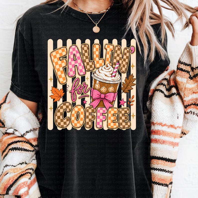 May include: Black t-shirt with the text "Fallin' for Coffee" in a graphic design. The design includes a coffee cup with whipped cream, a pink bow, and autumn leaves. The text uses checkered and solid fonts, with pink and brown colours.