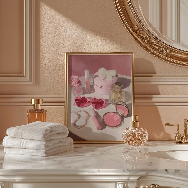 May include: A vanity scene featuring a framed artwork with pink heart-shaped sunglasses, a jewelry box, and perfume bottles. A stack of white towels and a decorative perfume bottle are in the foreground. The color palette is soft pink and gold.