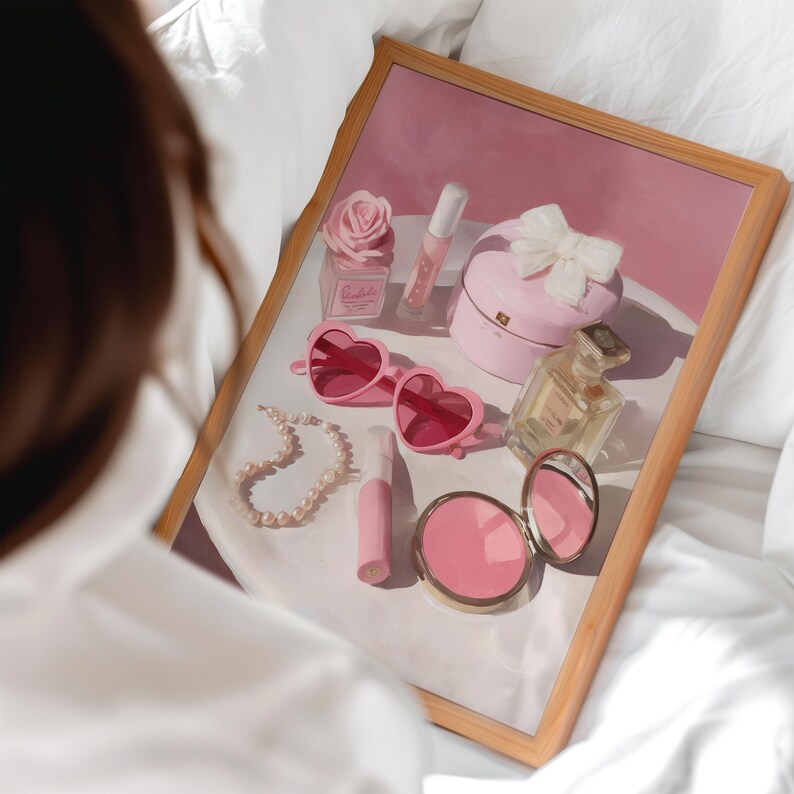 May include: A collection of pink accessories, including heart-shaped sunglasses, a pearl necklace, a compact mirror, and a perfume bottle, are arranged on a white surface. A pink gift box with a white bow and a rose-shaped decoration add to the feminine aesthetic.