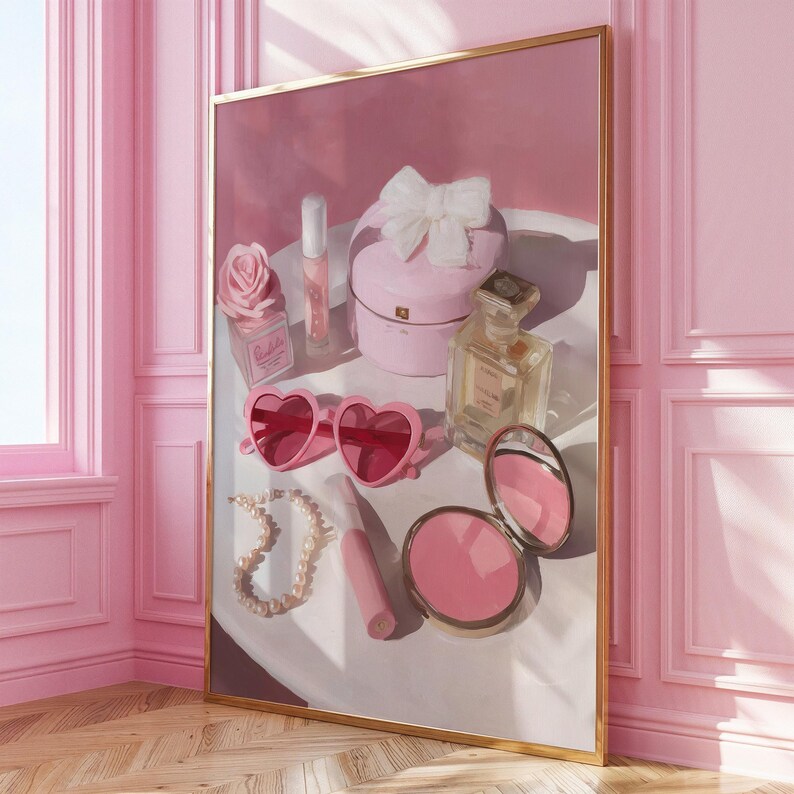 May include: A framed artwork featuring a collection of pink beauty products. The composition includes heart-shaped sunglasses, a compact mirror, a perfume bottle, a jewelry box with a bow, and a pearl necklace. The color palette is predominantly pink.
