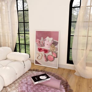 May include: A framed print featuring a collection of pink accessories, including heart-shaped sunglasses, a compact mirror, perfume, and a jewelry box. A book with the word "CHANEL" is on a glass table.