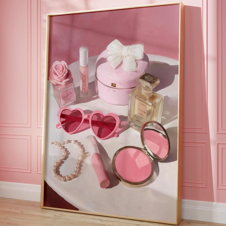 May include: A framed artwork featuring a collection of pink accessories. Heart-shaped sunglasses, a pearl necklace, a compact mirror, perfume, and a jewelry box with a bow are arranged on a white surface. A pink rose-shaped perfume bottle and lip gloss are also present.