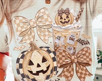 Puede incluir: Una camiseta beige con un estampado gráfico de dos grandes lazos a cuadros, una calabaza de Halloween, un vaso de bebida con nata montada y una pequeña calabaza, además de pequeñas ilustraciones de fantasmas y murciélagos en tonos tierra.