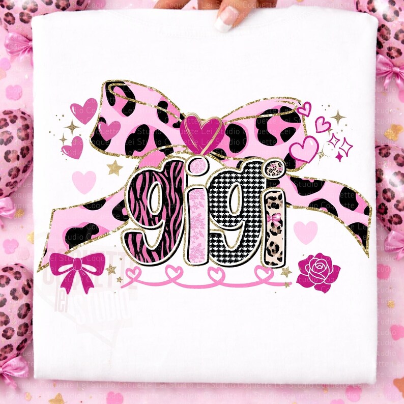 K&ouml;nnte beinhalten: Wei&szlig;es T-Shirt mit dem Namen "GIGI" in einem dekorativen Design. Die Buchstaben haben Zebra-, Hahnentritt- und Leopardenmuster. Eine rosa Schleife mit einem schwarz-rosa Kuhdruck, Herzen und eine Rose vervollst&auml;ndigen das Design.