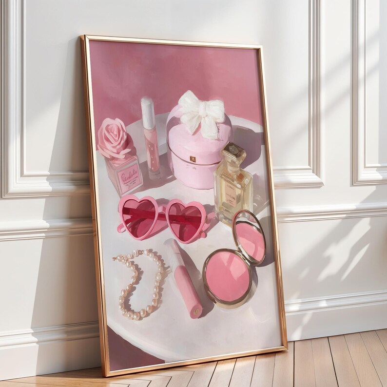 May include: A framed print featuring a collection of beauty products and accessories. The composition includes pink heart-shaped sunglasses, a pearl necklace, a compact mirror, a perfume bottle, and a pink box with a white bow. The color palette is soft pink and gold.