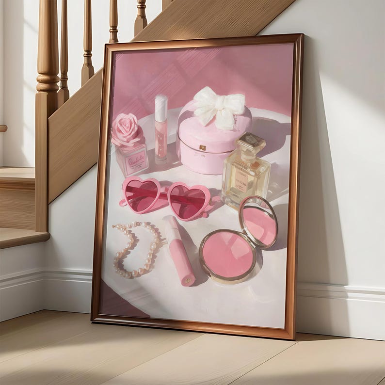 May include: A framed artwork featuring a collection of pink accessories. The composition includes heart-shaped sunglasses, a pearl necklace, a compact mirror, perfume bottles, and a heart-shaped box with a bow. The color palette is soft, with pink and white tones.